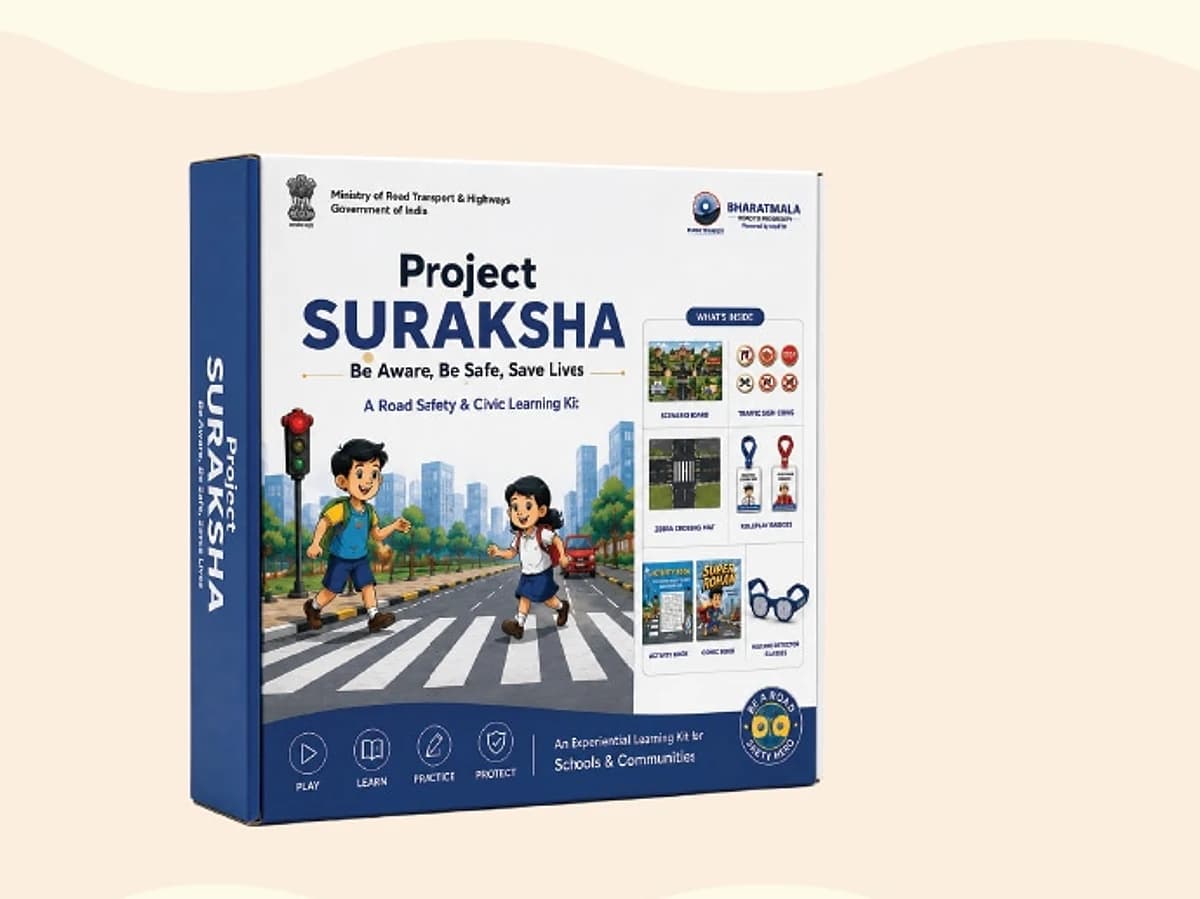 The Road Safety retail box, navy blue, showing two schoolchildren crossing at a zebra crossing beside a traffic signal. The box itself is printed "Project SURAKSHA", the kit's earlier name